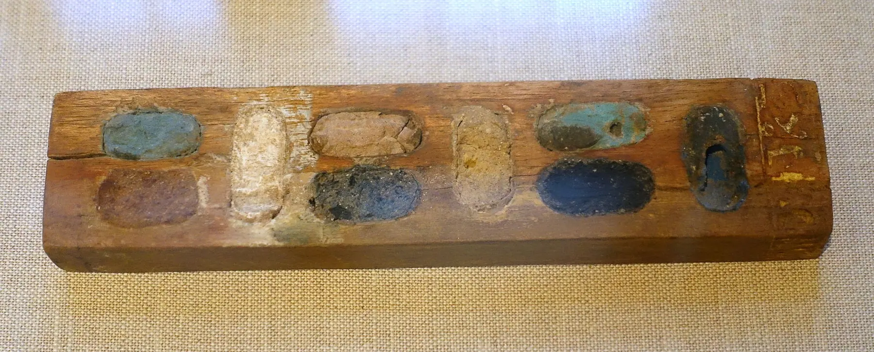 Ancient wooden painting palette with surviving pigment cakes